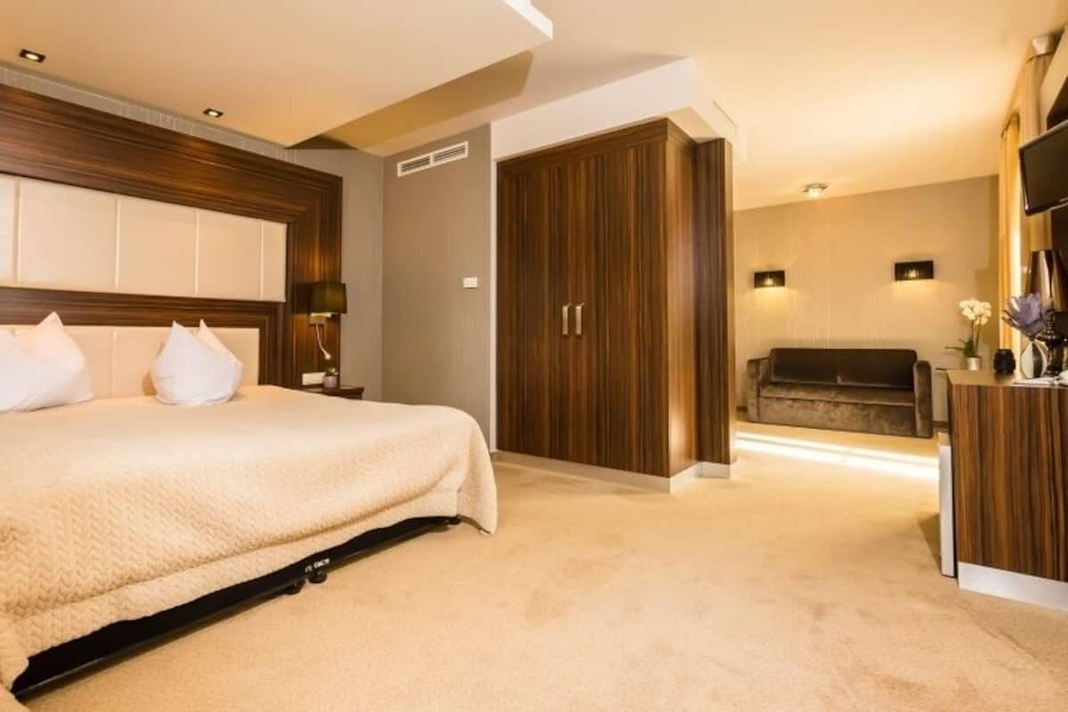 A bedroom with a bed, a wardrobe, a desk, and a television.