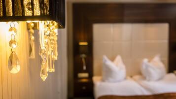 A hotel room with a bed, white pillows, and a wall-mounted light fixture.