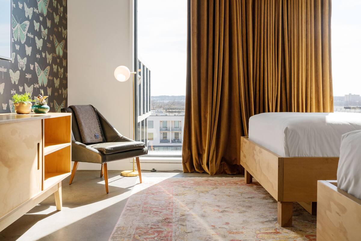 Une chambre d’hôtel moderne dotée d’une grande fenêtre, d’un lit, d’un bureau et d’une chaise.
