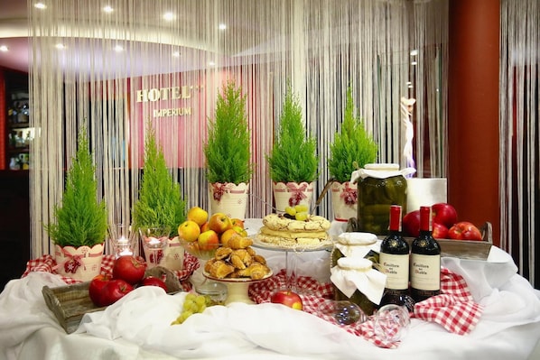 A hotel reception area with a table set for a buffet, featuring various food items and wine bottles.