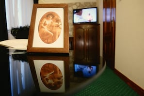 A framed photograph on a reflective surface with a television in the background.