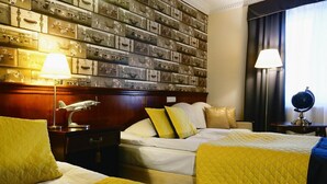 A hotel room with two beds, a wall of suitcases, and a nightstand with a lamp.