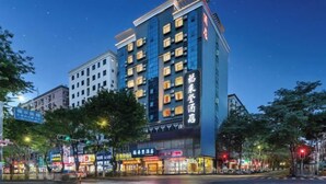 A multi-story hotel with illuminated signage, a prominent entrance, and a street view with traffic lights and trees.