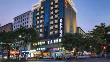 A multi-story hotel with illuminated signage, located at a city intersection.