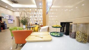 A hotel lobby with a reception desk, seating area, and a decorative wall with framed pictures.