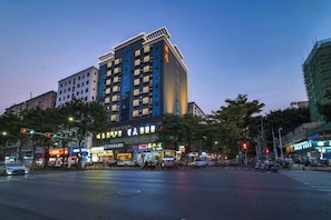 A multi-story hotel with a modern design, located at a busy intersection with visible traffic lights and street signs. - Fulaideng Hotel (SHENZHEN)
