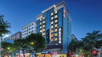 A multi-story hotel with a modern facade, illuminated signage, and a prominent entrance at street level.
