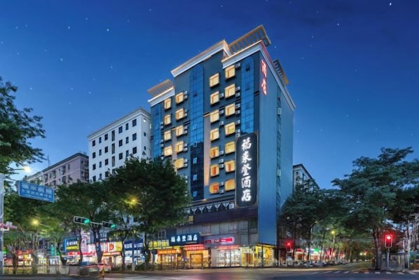 A multi-story hotel with a modern facade, illuminated signage, and a prominent entrance at street level. - Fulaideng Hotel (SHENZHEN)