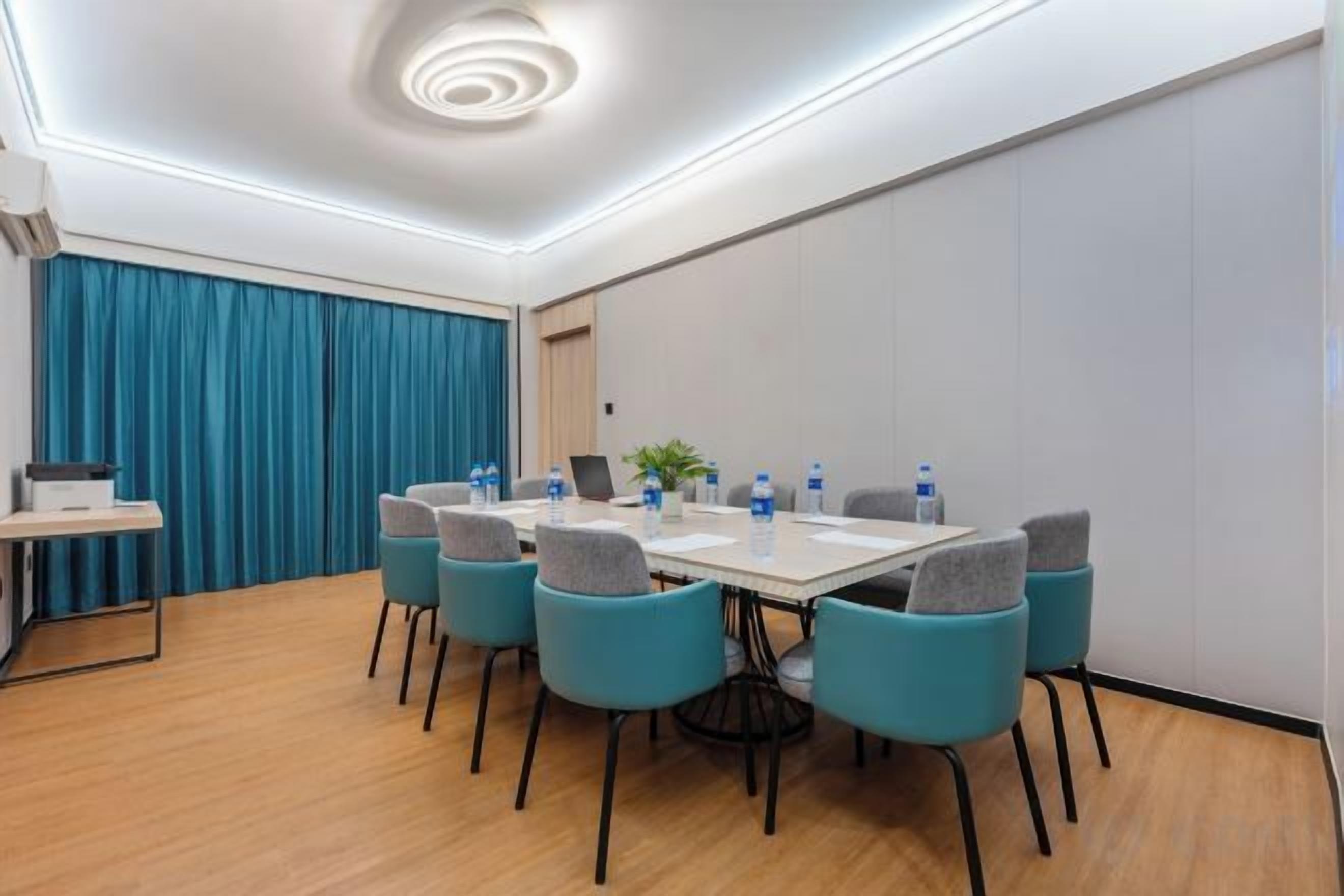 Un salón de conferencias con una mesa redonda, seis sillas y una computadora portátil.