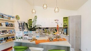 Een moderne keuken met een centraal eiland, groene barstoelen, hanglampen en diverse decoratieve objecten.