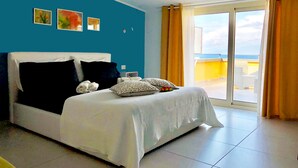 Een slaapkamer met een groot bed, uitzicht op de lucht en een balkon.