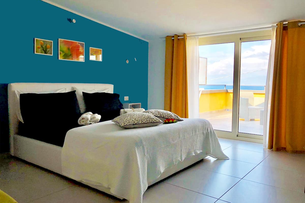 Un dormitorio con una cama grande, vistas al cielo y un balcón.