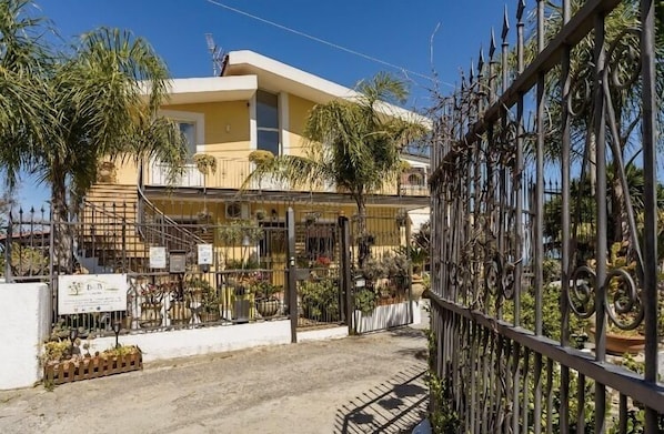 A two-story building with a balcony, surrounded by a metal fence with decorative elements. - B&B Il Giardino sul Mare (Briatico)