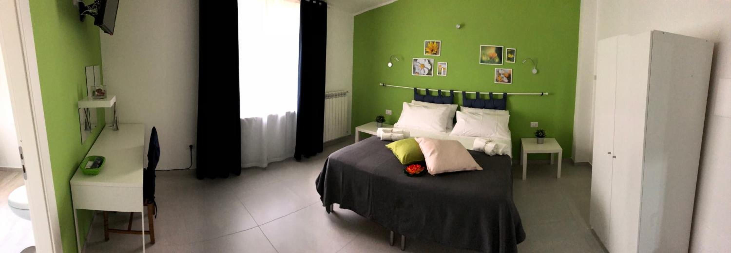 Una camera da letto con un letto, una scrivania, una sedia e una finestra con tende.