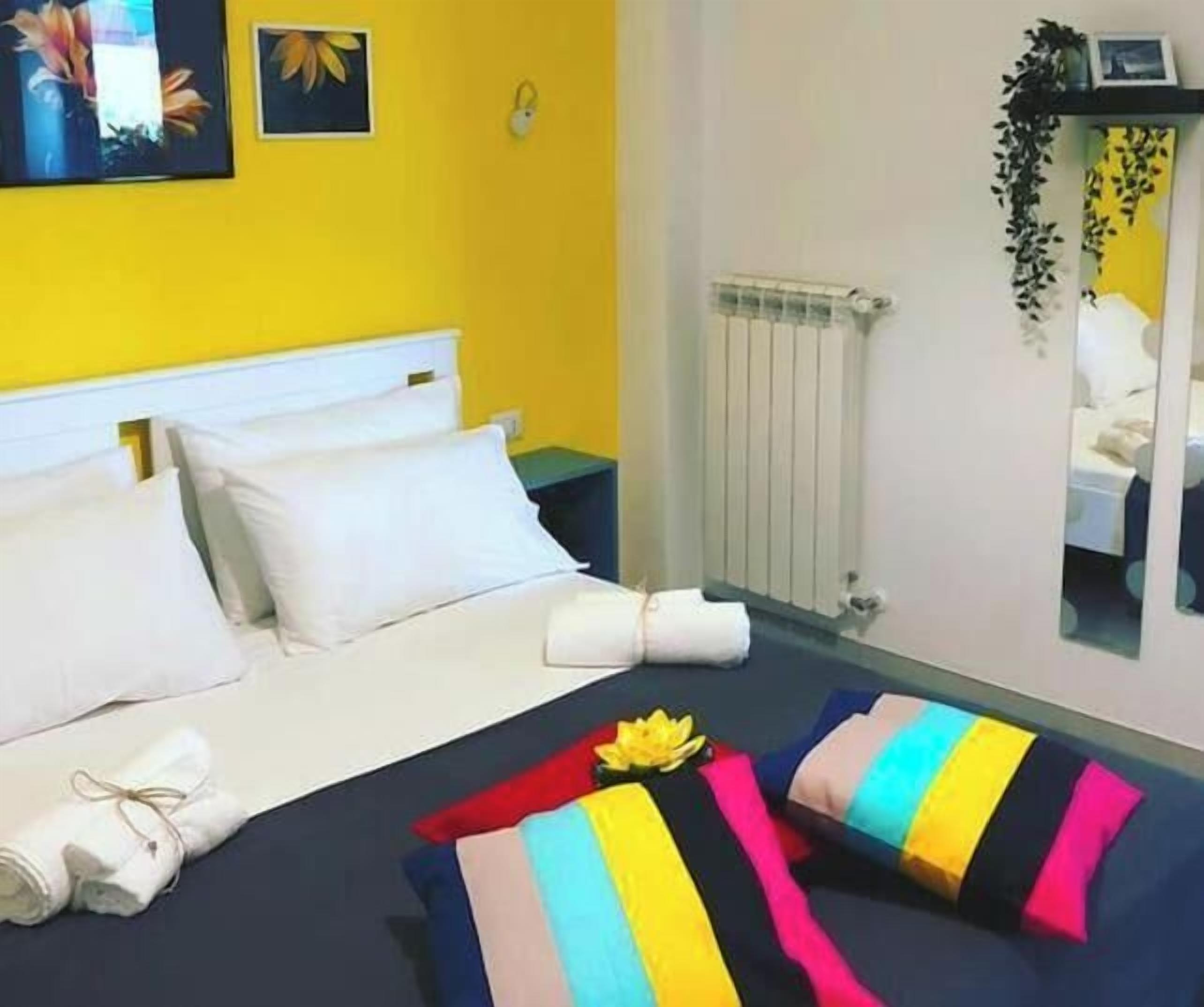 Habitación de hotel con cama, almohadas, una toalla enrollada, un radiador y un espejo.