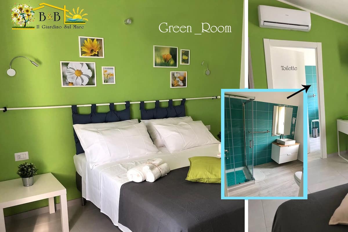 Habitación de hotel con decoración verde, que incluye una cama, un escritorio, ducha y baño.