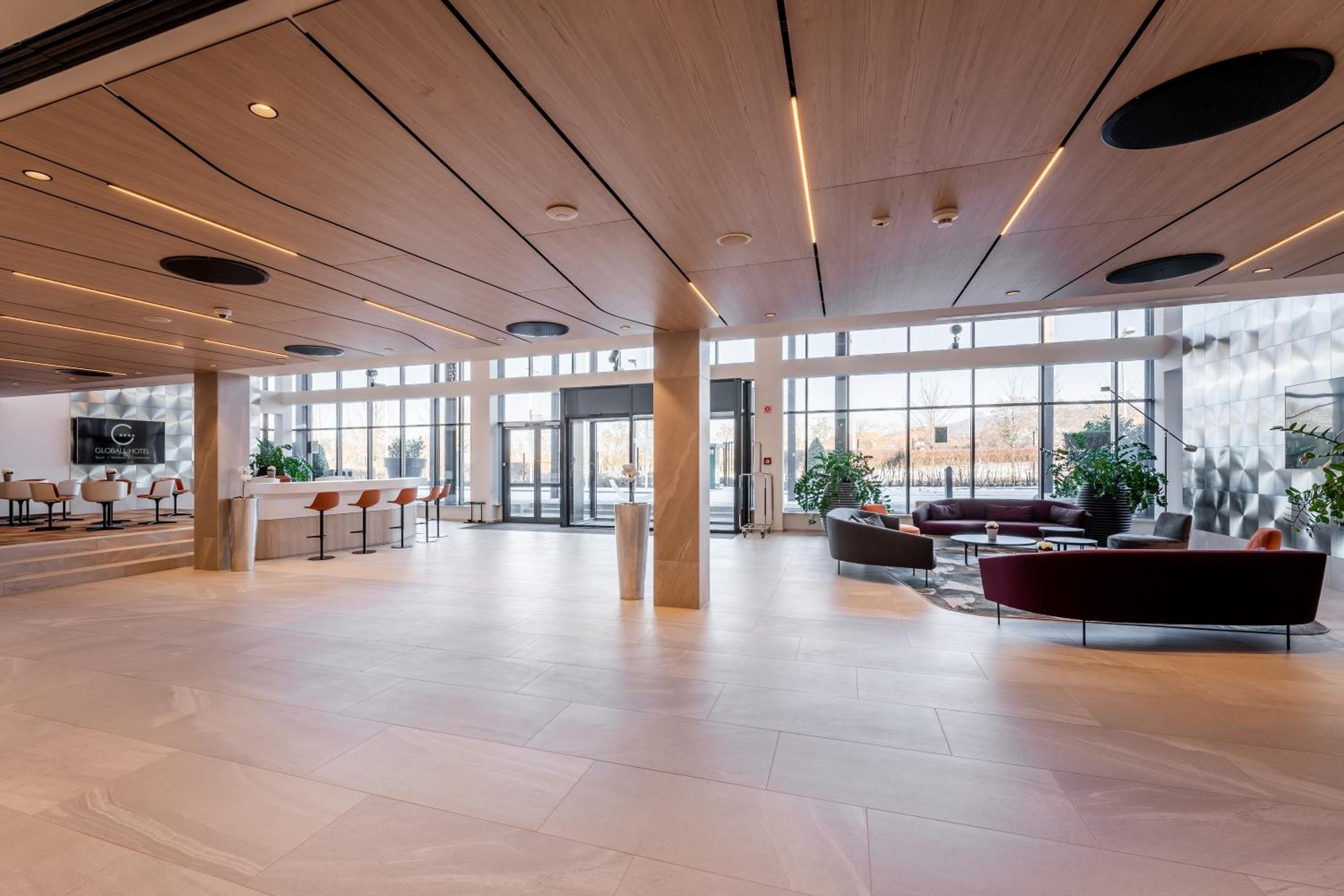 A spacious lobby with a modern design, featuring a bar area, seating arrangements, and large windows providing views.