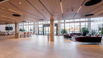 A spacious lobby with a modern design, featuring a bar area, seating arrangements, and large windows providing views.