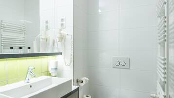 A modern bathroom with a large mirror, white fixtures, a toilet, and a towel rack.