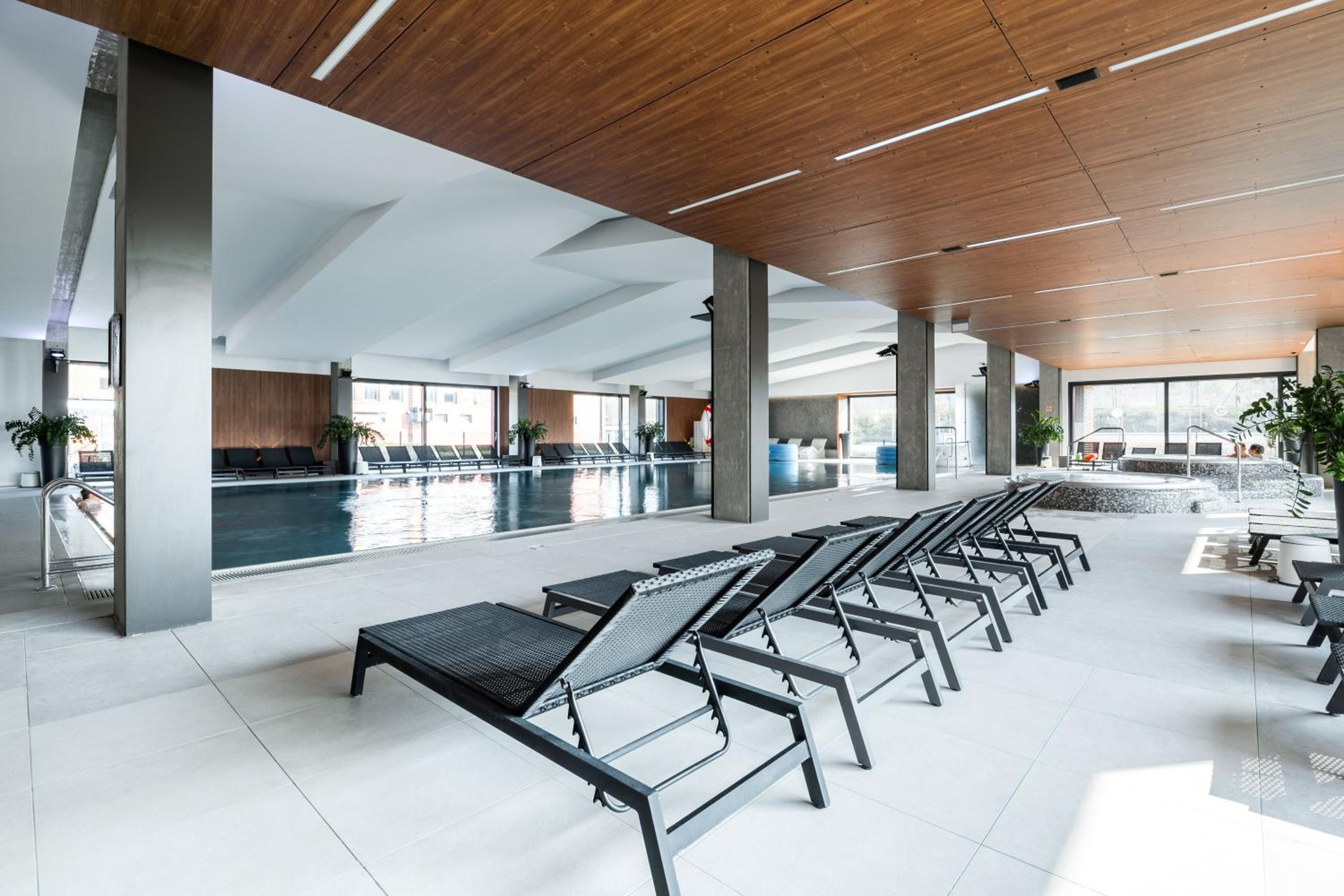 A modern indoor pool area with lounge chairs and a clear view of the pool.
