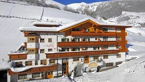 Un hotel de varios pisos con un telesilla, rodeado de montañas nevadas.