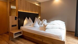 Una habitación de hotel moderna con estructura de cama de madera, cabecero integrado y un pequeño banco de madera.
