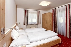 A hotel room with a wooden bed, a wardrobe, and a window with curtains.