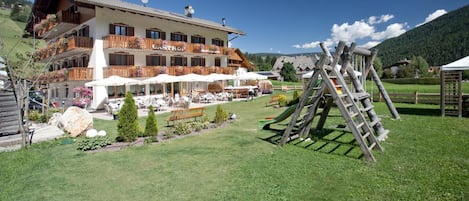 A hotel with outdoor seating and a wooden play structure.
