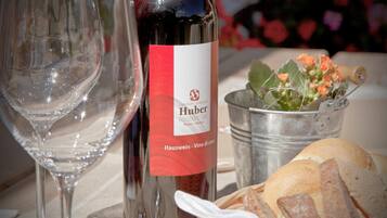 Une bouteille de vin avec une étiquette, un verre, un seau en métal rempli de fleurs et un panier de pain.