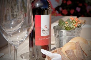 Una botella de vino con etiqueta, una copa, un cubo metálico con flores y una cesta de pan.