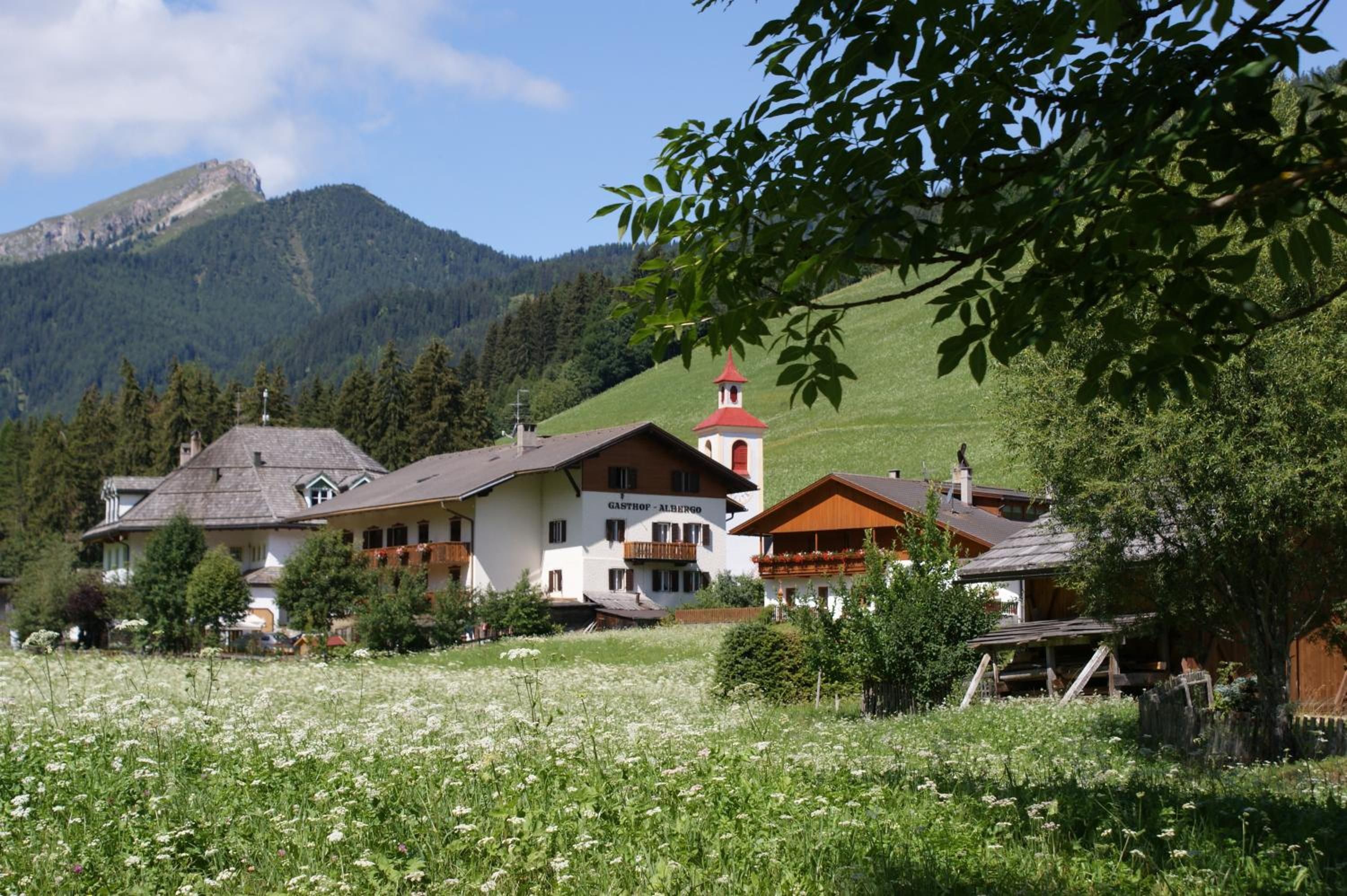 Ein Bergdorf mit traditioneller Architektur, darunter ein Gebäude mit rotem Dach und einem Glockenturm.