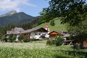 A mountain village with traditional architecture, including a building with a red roof and a bell tower.