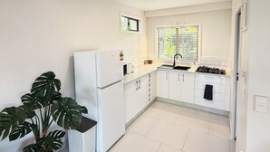 Una cocina moderna con armarios blancos, estufa integrada y una ventana con persianas.