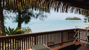 Una terraza de madera con vista a una playa y una isla.