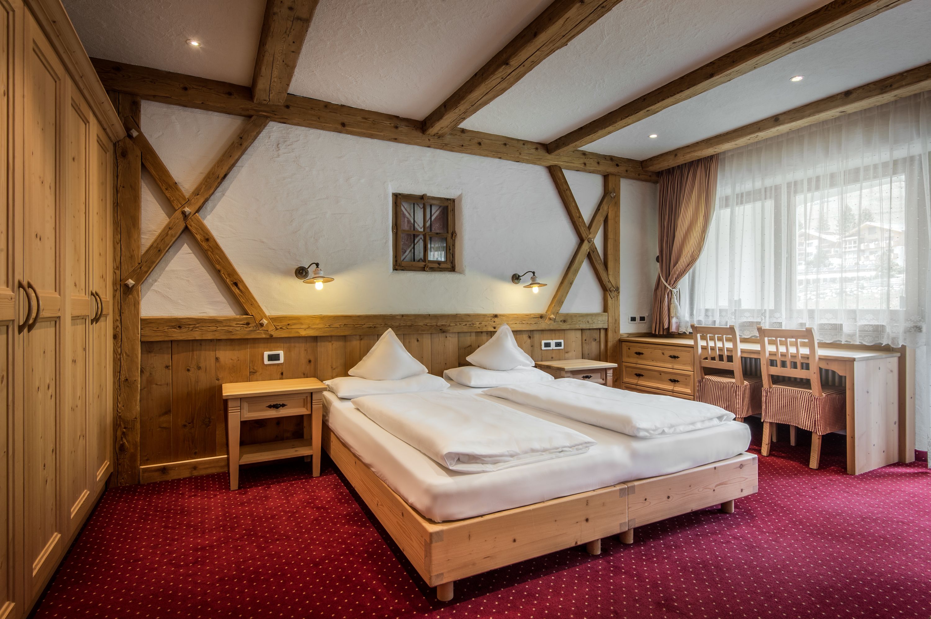 Un dormitorio con estructura de madera, una cama, un escritorio y sillas.