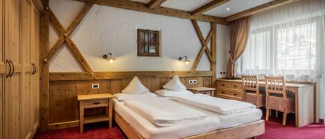 Un dormitorio con estructura de madera, una cama, un escritorio y sillas.