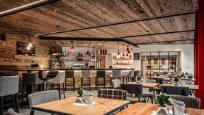A modern restaurant with wooden ceiling, red pendant lights, and a bar area. - Hotel Gran Ciasa (Corvara in Badia)