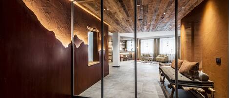 Een modern interieur met een houten plafond, glazen wanden en een gezellige zithoek met een bank en kussens.