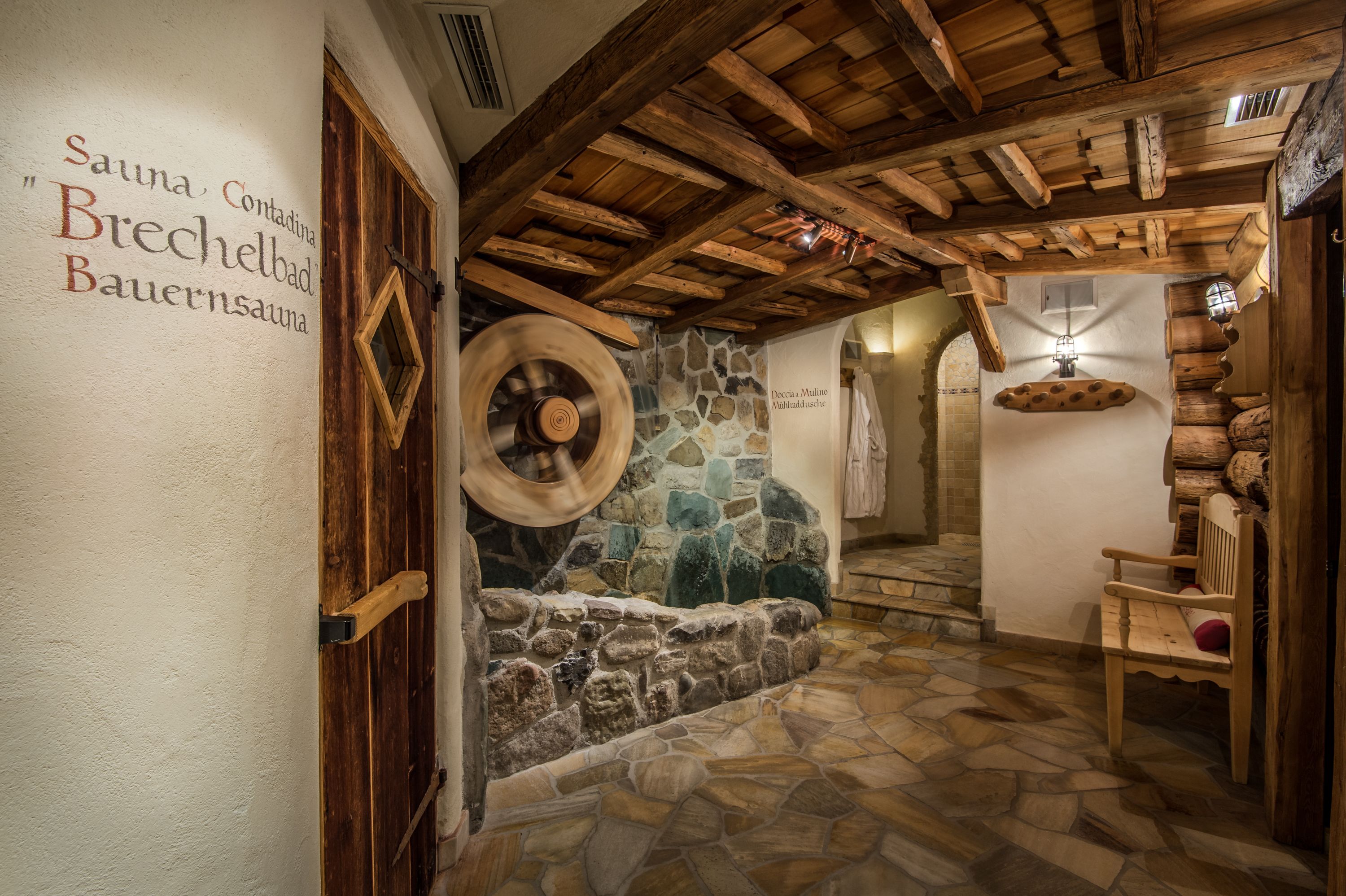 A stone-walled sauna area with wooden beams and a bench.