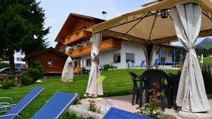 Un hotel con terraza al aire libre, piscina y vistas a la montaña.