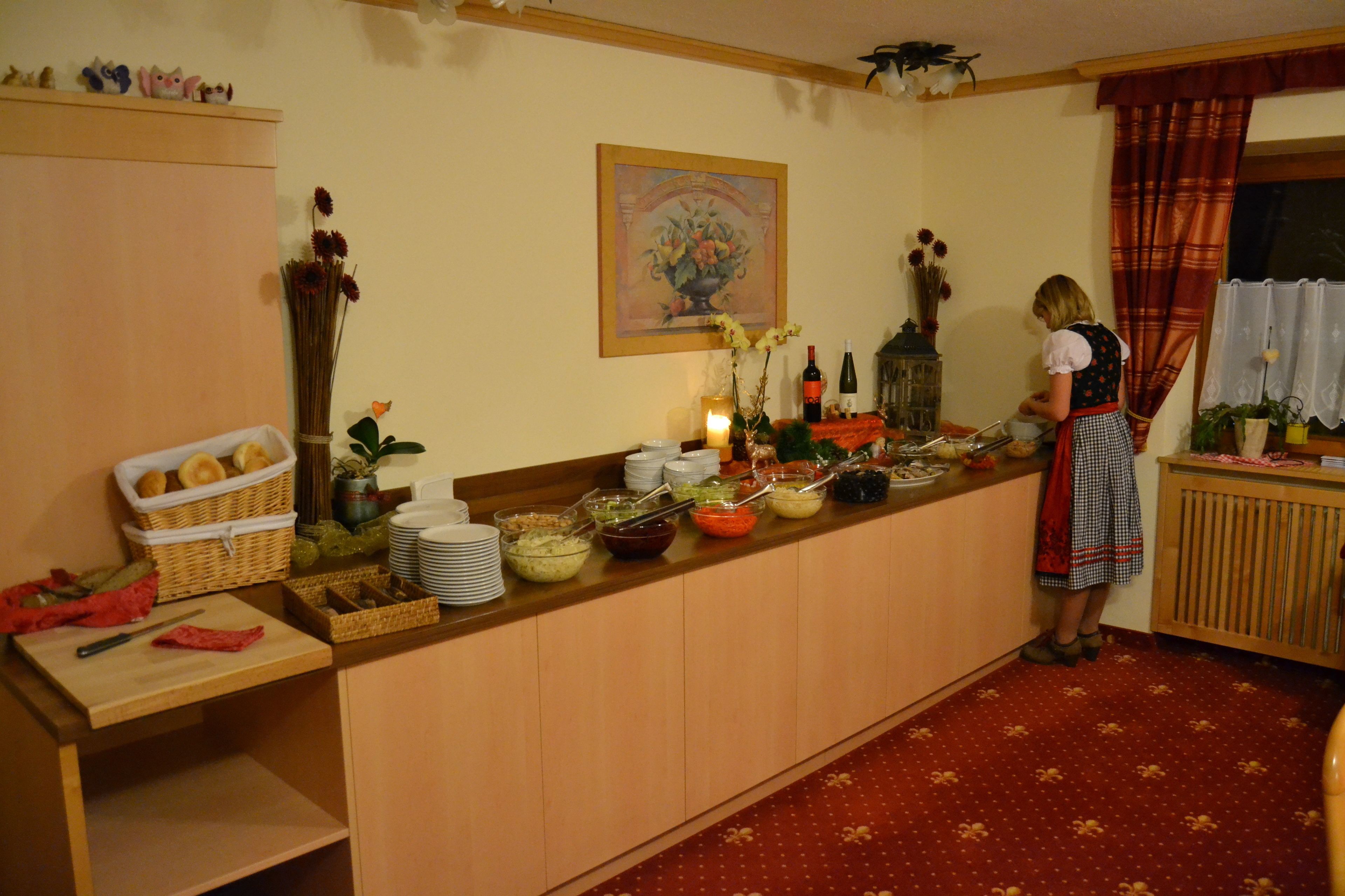 Mesa de buffet con diversos alimentos y una persona sirviendo.