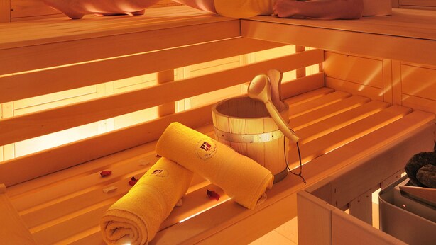 Una sauna de madera con bancos y un banco con una toalla y un cubo.