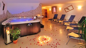 Un espacio de spa con una bañera de hidromasaje, sillas reclinables y una planta en maceta.