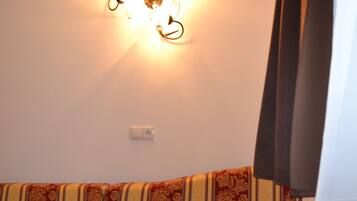 A room with a sofa, a wall-mounted light fixture, and a power outlet.