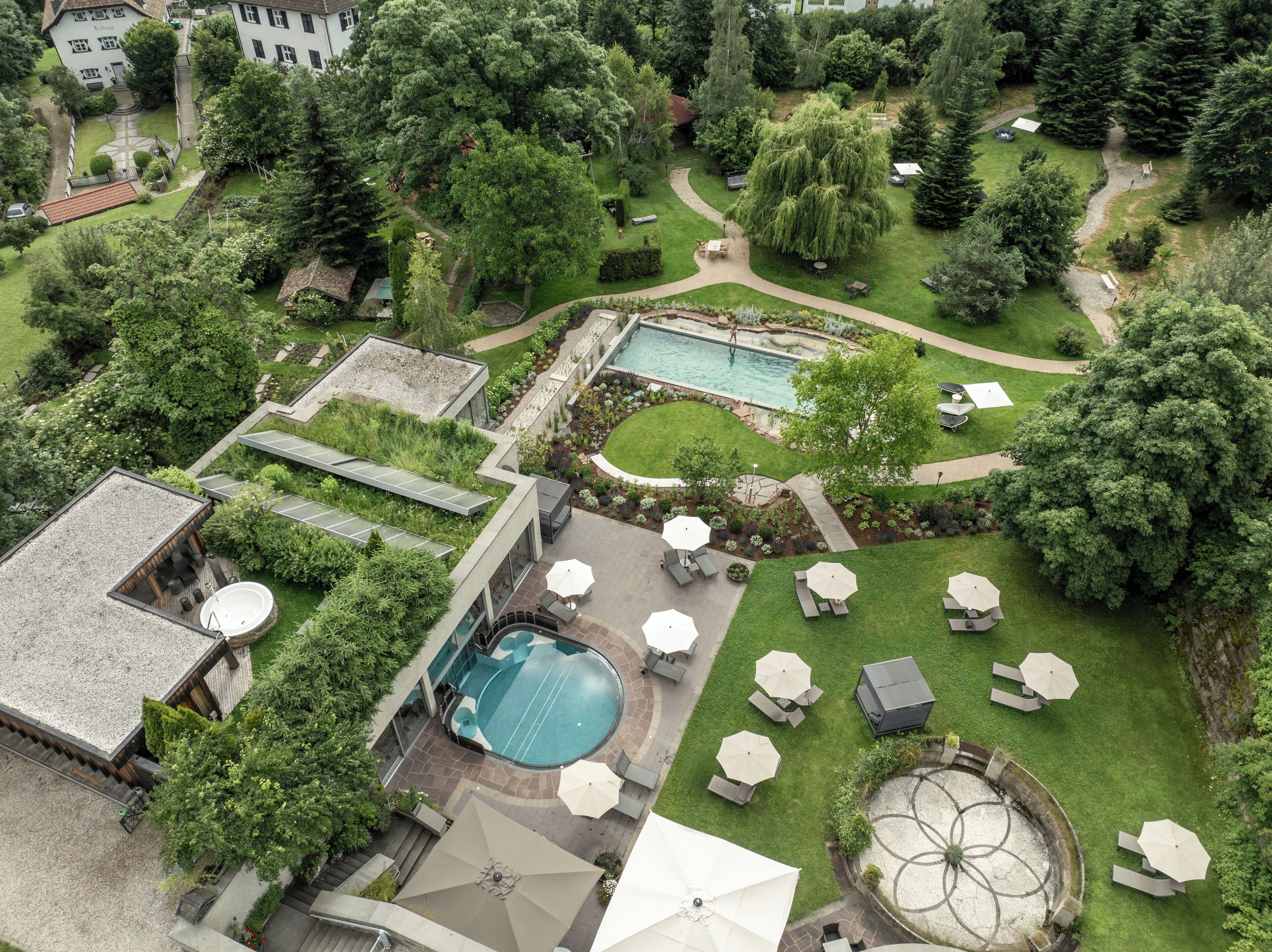A rooftop pool area with multiple swimming pools, sun loungers, and umbrellas.