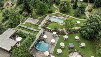 A rooftop pool area with multiple swimming pools, sun loungers, and umbrellas.