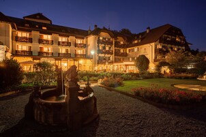 Un hotel con varios balcones, una fuente y un jardín bien cuidado.