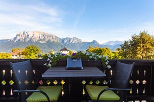 Terraço com mesa e cadeiras, vista para uma paisagem montanhosa.