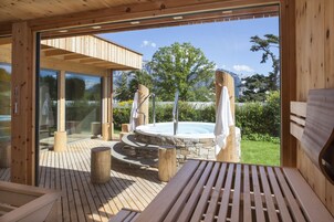 Una terraza de madera con un jacuzzi, escalones de piedra y vistas a la montaña.
