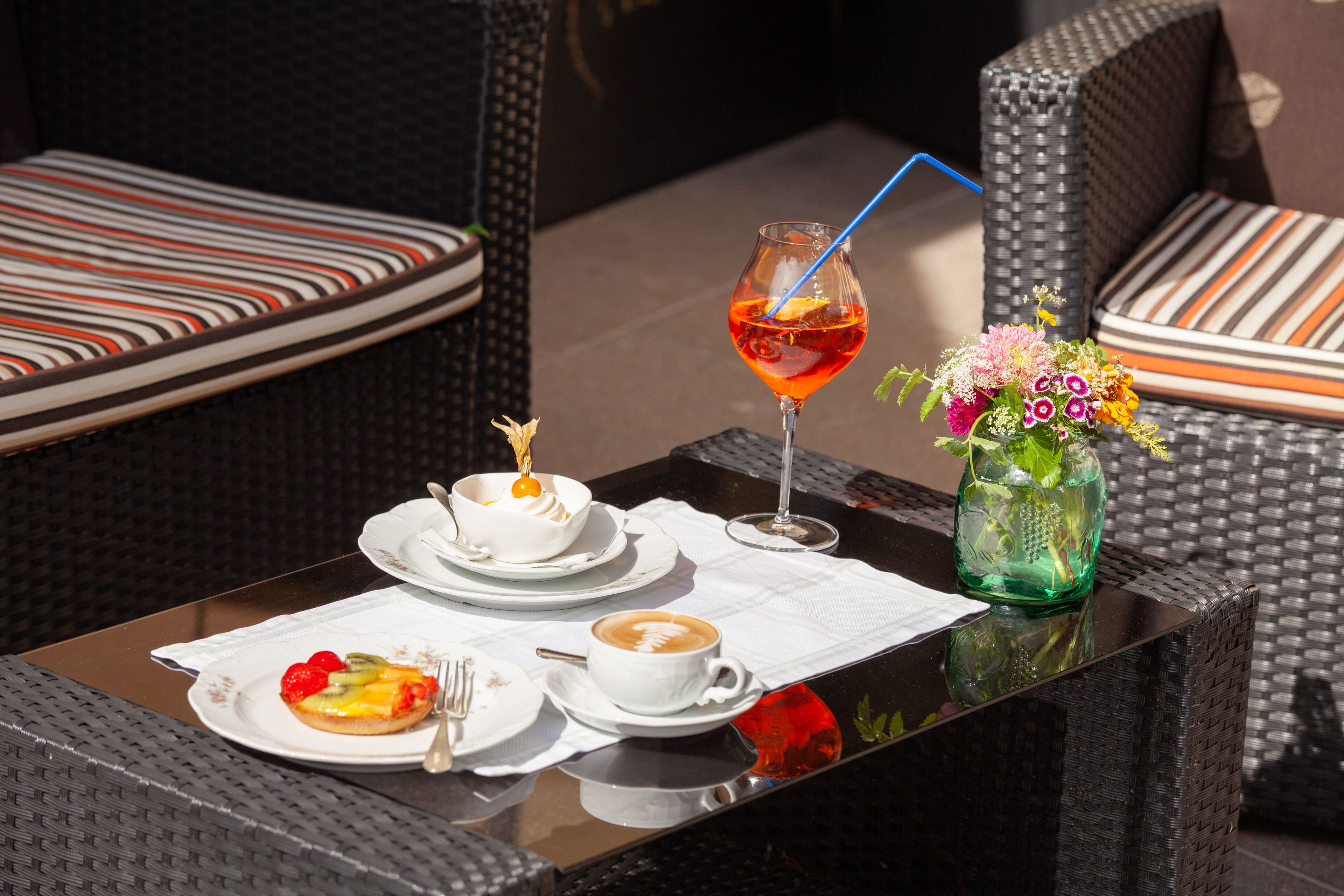 A dining table with a dessert plate, a cup of coffee, and a glass of red drink.